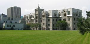 Exterior view of the limestone structure built in 1874 featuring pointed arches, buttresses, decorative quoins, crenellated towers and oriel windows.