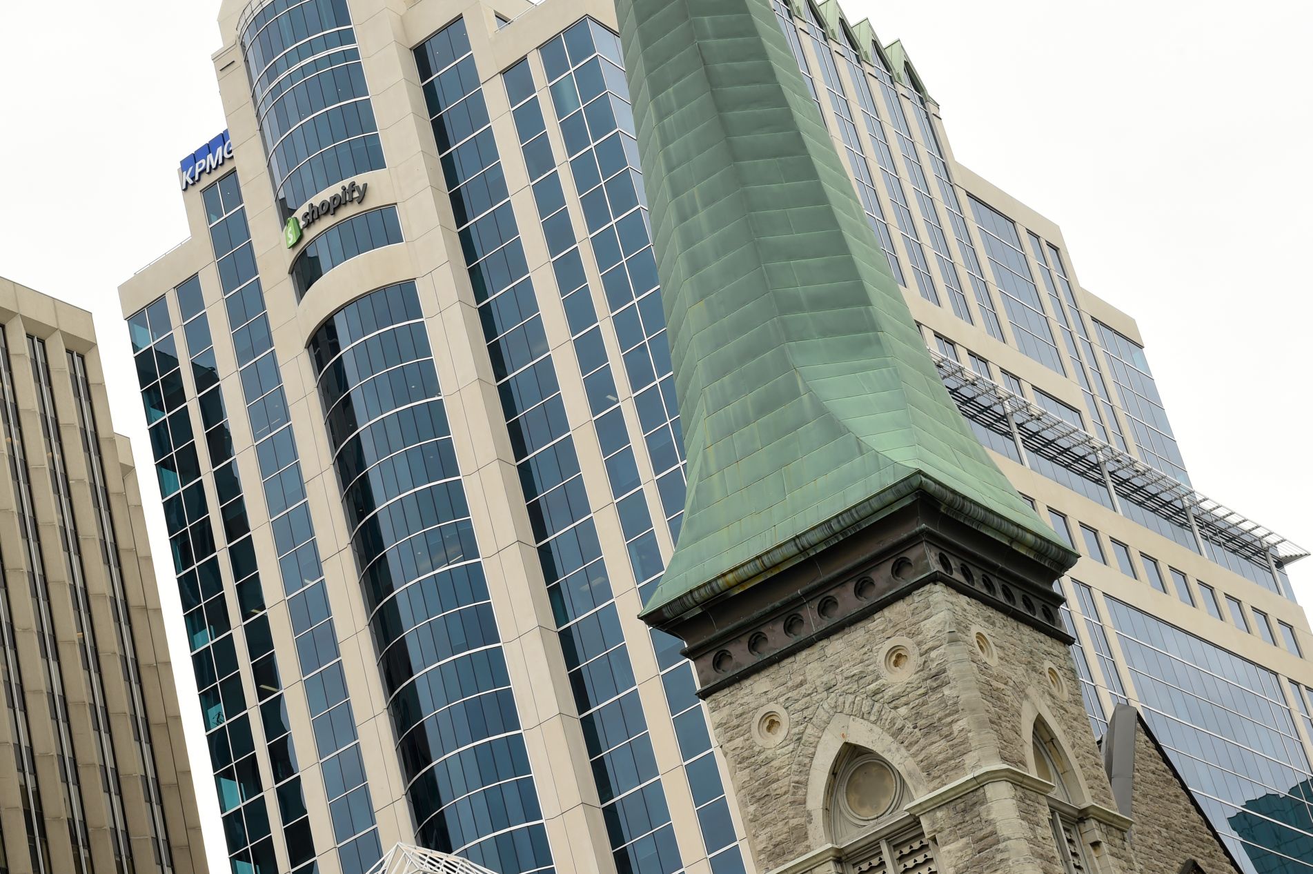 Exterior view of the glass Shopify building and a church steeple.